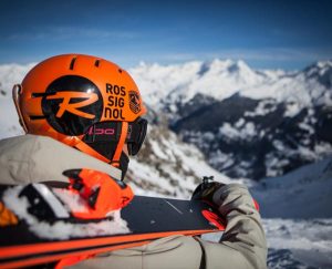 Mann mit Rossignol Skihelm und Alpin Ski blickt in der Ferne auf die Berge