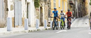 Drei Männer fahren auf Roadbikes durch eine Stadt mit alten Häusern
