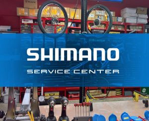 Logo Shimano Service Center, im Hintergrund Bike zur Prüfung in der Fahrradwerkstatt